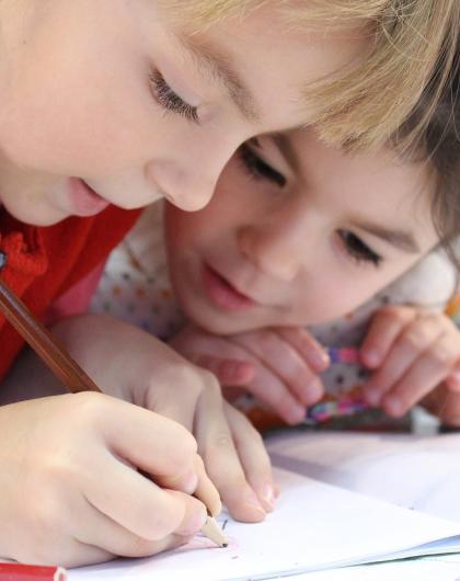 Image d'illustration pour l'atelier. Le visuel montre deux petites filles penchées sur une feuille. Elles sont en train d'écrire. 