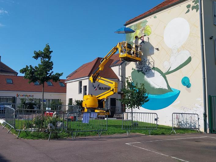 Le street artist Eskat au travail sur une fresque Un mur Une oeuvre à Fontenay-Mauvoisin